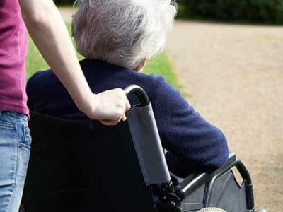 Woman pushing elderly woman in wheelchair concerned about when nursing home abuse goes unreported