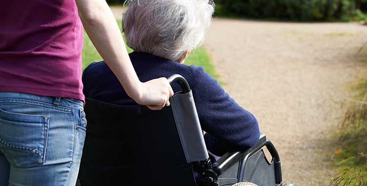 Woman pushing elderly woman in wheelchair concerned about when nursing home abuse goes unreported