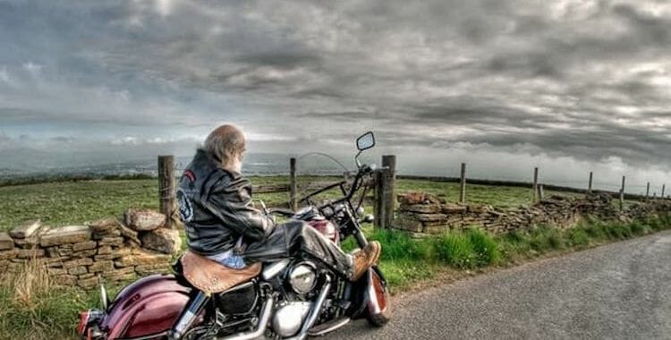This older man sitting on his motorcycle pulled on the side of the road represents the dangers of older motorcycle drivers